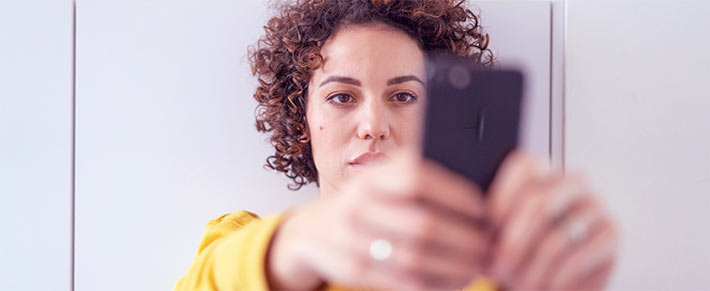 Frau ist schaut gefühlskalt auf ihr HandyFrau ist schaut gefühlskalt auf ihr Handy