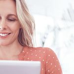 Single-Frau vor Rechner lächelt, das sie die Kontaktgarantie von ElitePartner hat