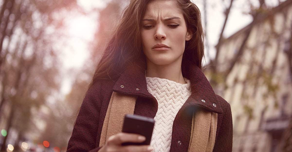 Frau schaut verwirrt in Ihr Handy weil sie nicht weiß wie sie einen Korb geben soll