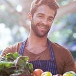 Mann beim Flirten lernen am Gemüsemarkt mit Obstkiste in der Hand