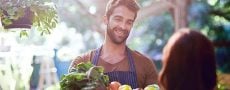 Mann beim Flirten lernen am Gemüsemarkt mit Obstkiste in der Hand