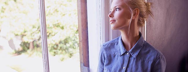 Frau schaut nachdenklich aus dem Fenster heraus als Symbolbild dafür Frauen zu verstehen