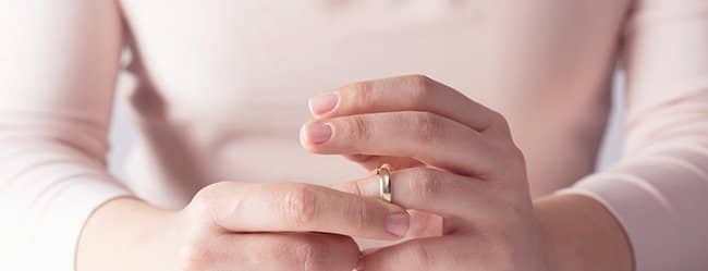 Hände einer Frau, die mit Ring am Finger spielt und sich fragt: "Warum heiraten?"