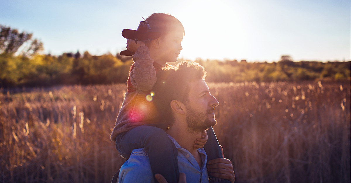 Emotionaler Mann in Gerstenfeld mit Kind auf seinen Schultern