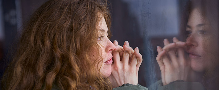 Frau schaut aus dem Fenster, überlegt wie sie Ex zurückgewinnen kann